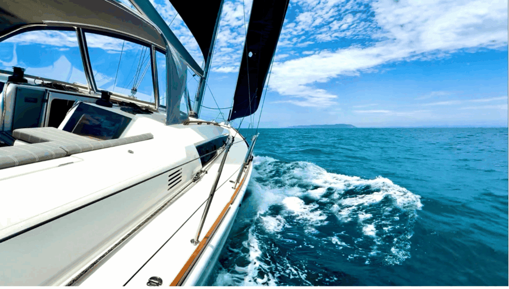 Sailboat sailing through crisp, blue water at sea. 