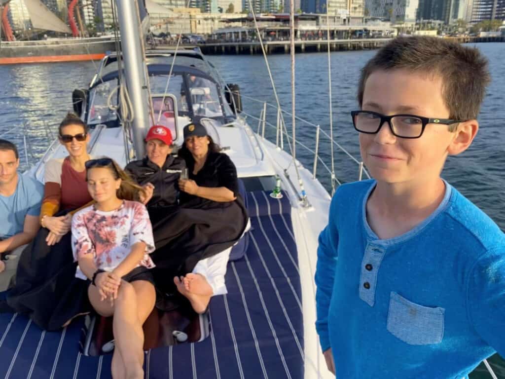 A boy and his family smile for the camera on the deck of the Riviera sailboat.