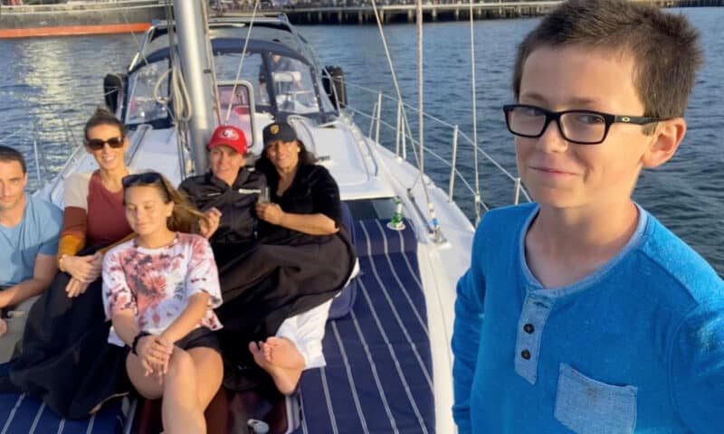 A boy and his family smile for the camera on the deck of the Riviera sailboat.