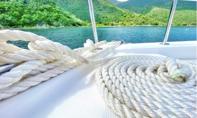 View from atop a catamaran, looking out on to a blue ocean with vibrant green hills in the background.