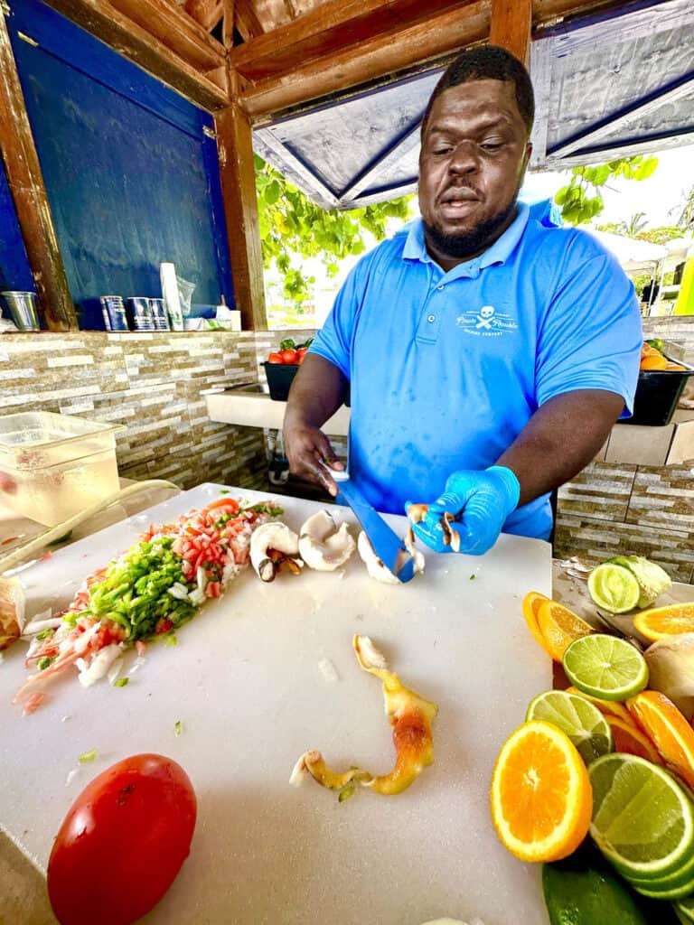 Man chopping and preparing food in an outdoor kitchen.