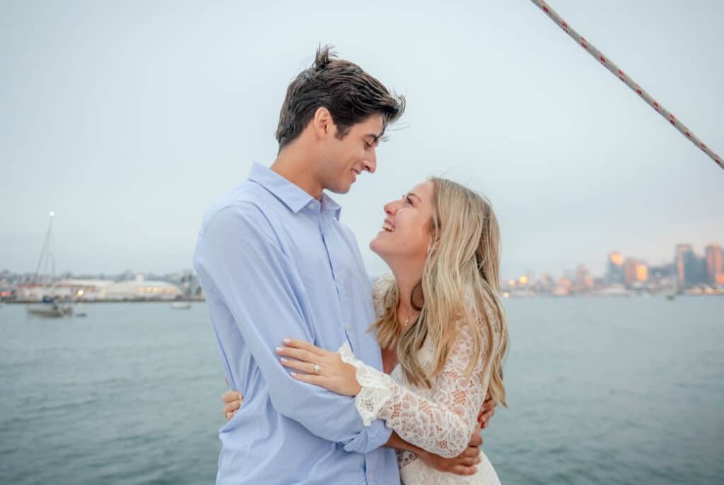 Couple embracing and looking into each others' eyes on a sailboat in the San Diego harbor.