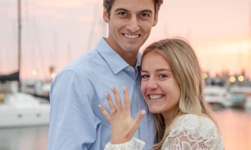 Newly-engaged couple with girl showing off her engagement ring at sunset on the San Diego bay.