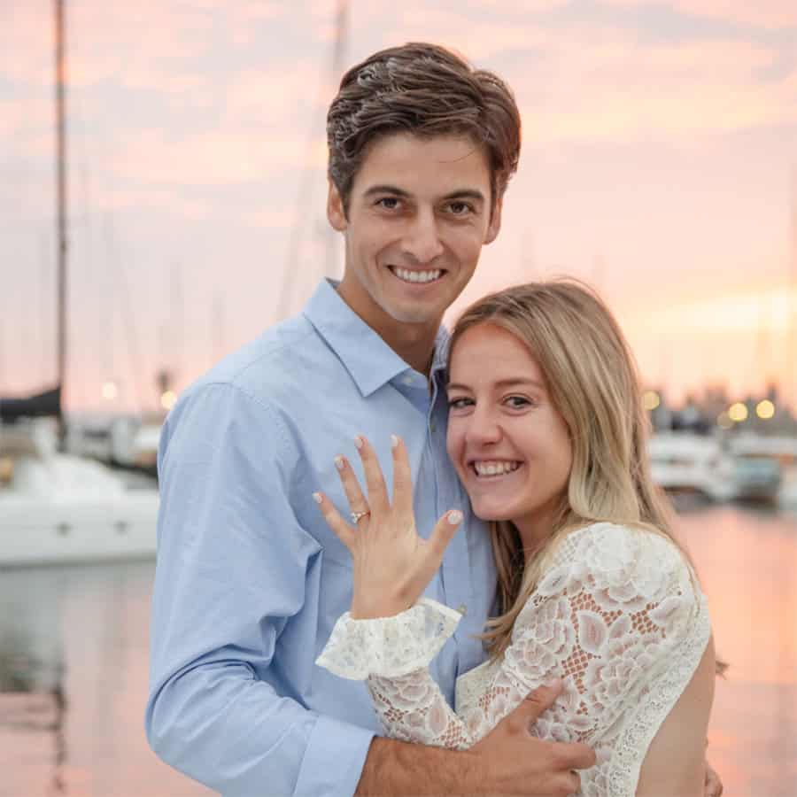 Newly-engaged couple with girl showing off her engagement ring at sunset on the San Diego bay.