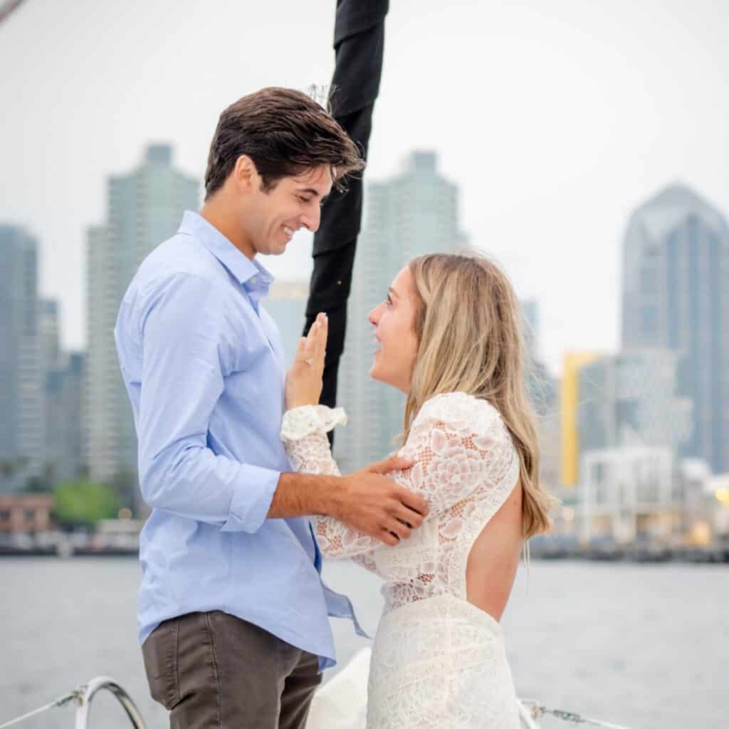 Couple embracing on the how of a sailboat in the San Diego bay after just getting engaged.