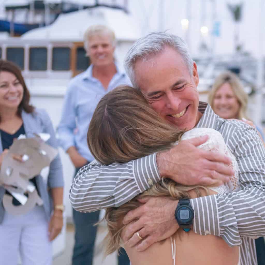 Daughter hugging her father at the dock after just getting engaged on a sailboat in the San Diego Bay.