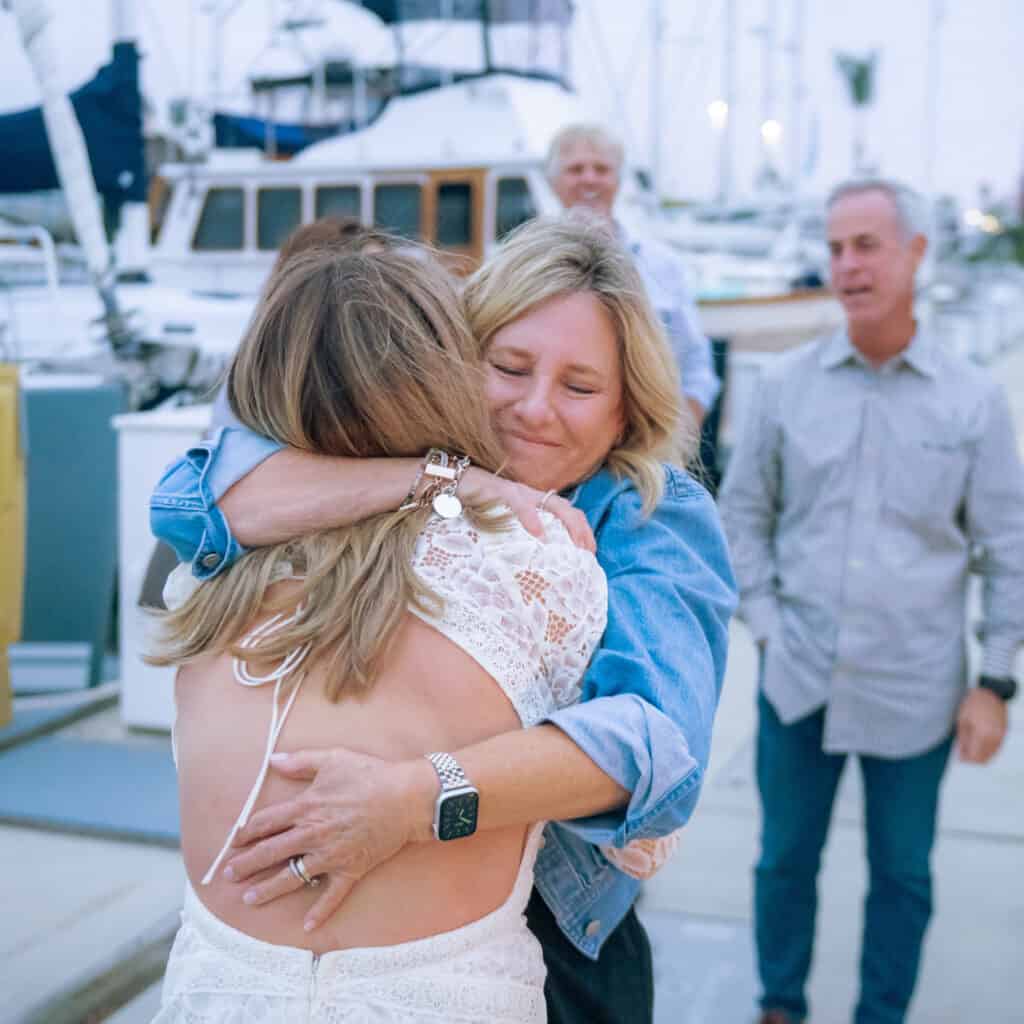 Daughter hugging her mother at the dock after just getting engaged on a sailboat in the San Diego Bay.