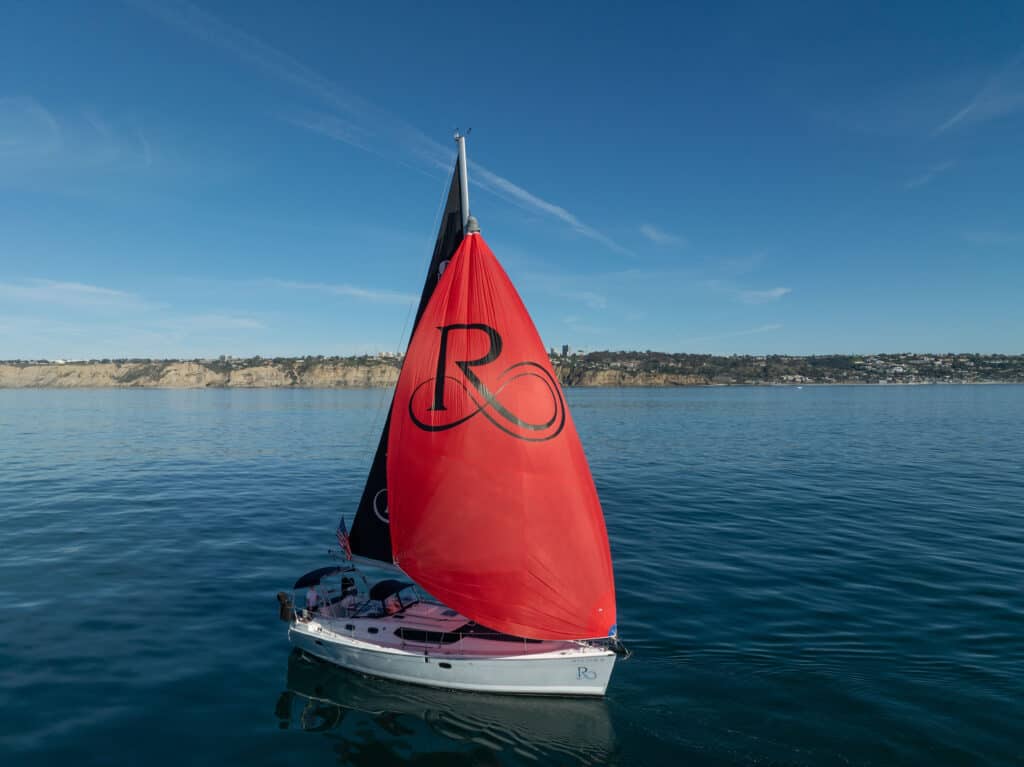 Riviera sailboat with red and blue sails on the Pacific Ocean