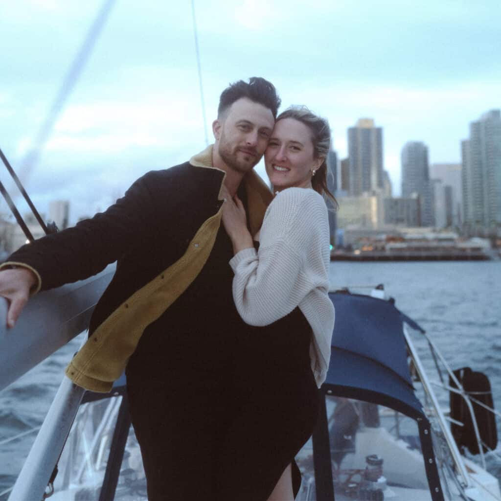 Couple posing together on the deck of the Riviera sailboat after getting engaged