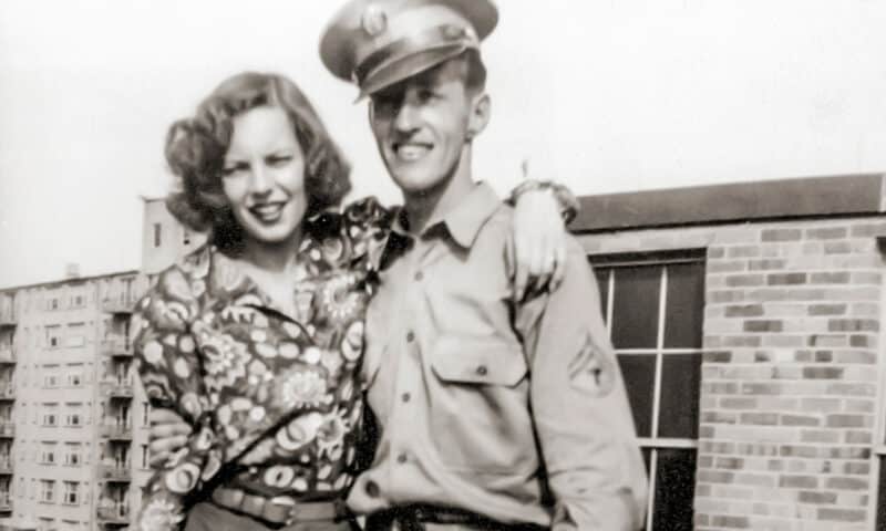 A World War 2 era photo of a man in uniform posting with a woman at his side