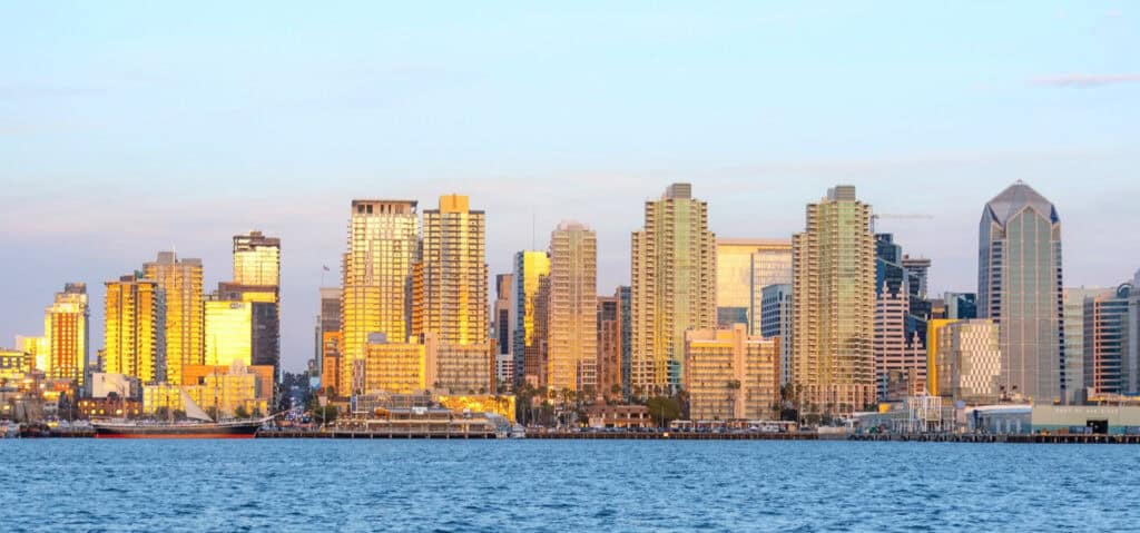 The San Diego city skyline during sunset with the Harbor water in the foreground.