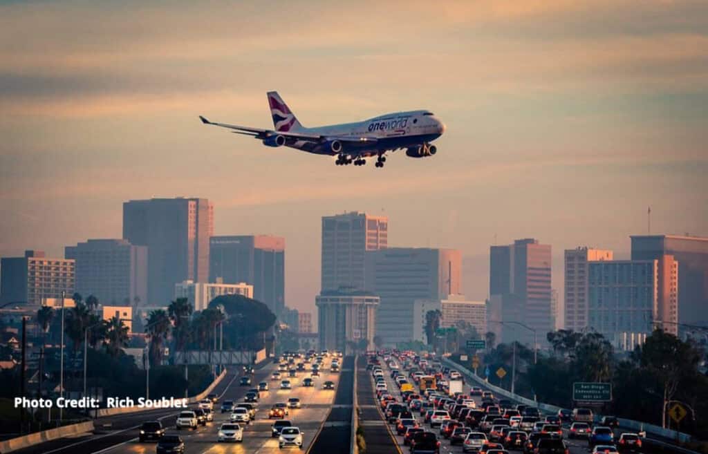 An airplane coming in over a busy highway as it prepares to land in San Diego.