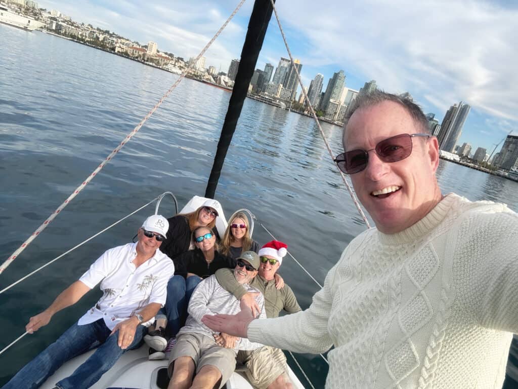 Captain Paul and his guests aboard the Riviera sailboat, with the San Diego skyline in the background.