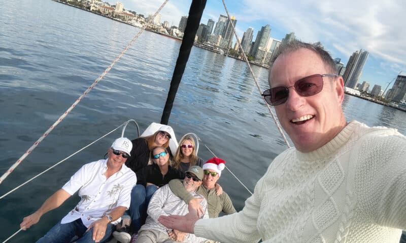 Captain Paul and his guests aboard the Riviera sailboat, with the San Diego skyline in the background.