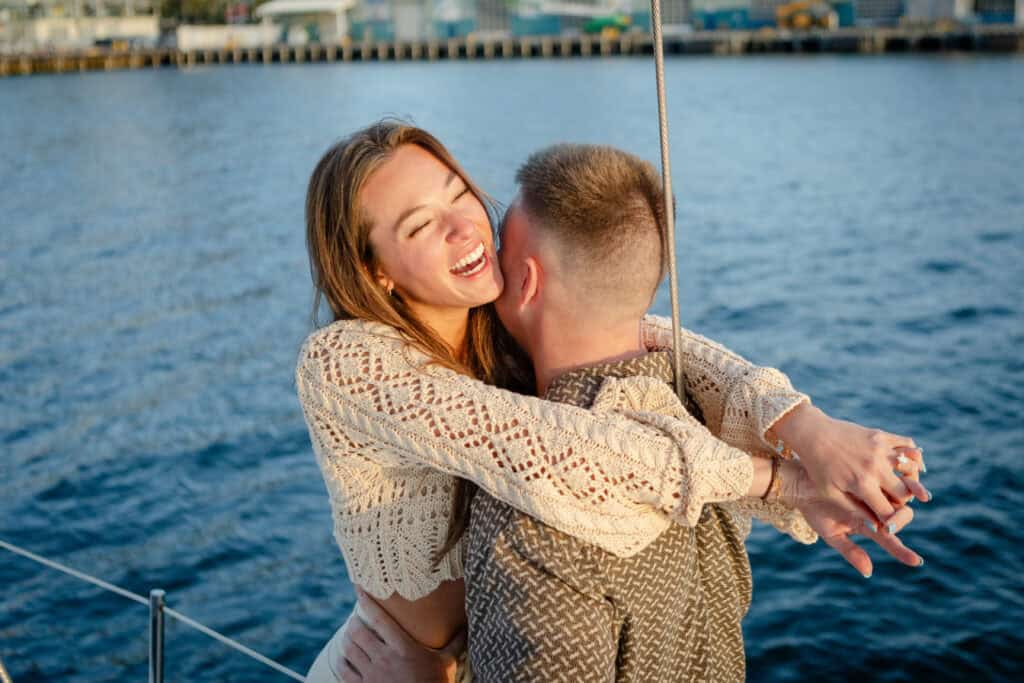 A couple hugging aboard the Riviera sailboat.