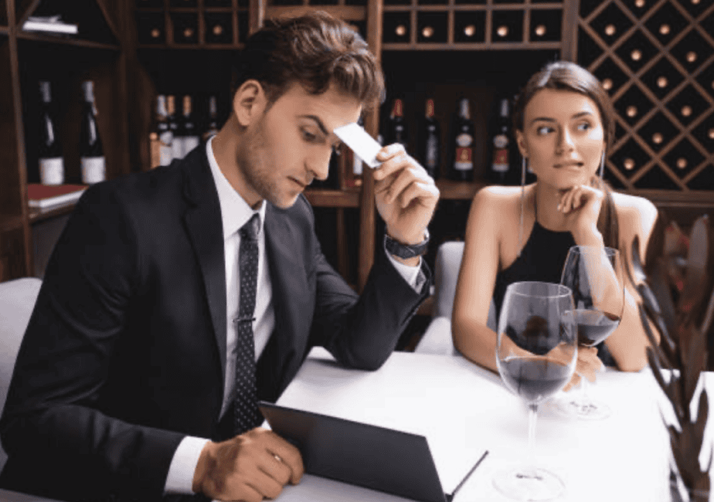 A couple at a fancy restaurant look stressed and unhappy as they pay their bill