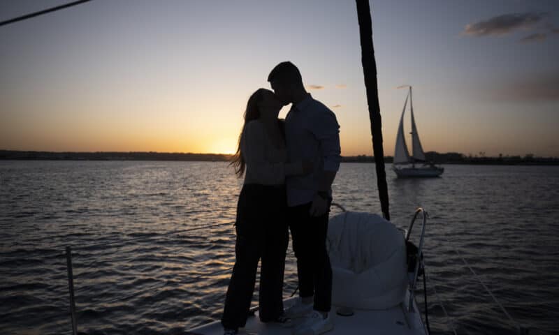 A couple embrace on the deck of the Riviera during a sunset sail.