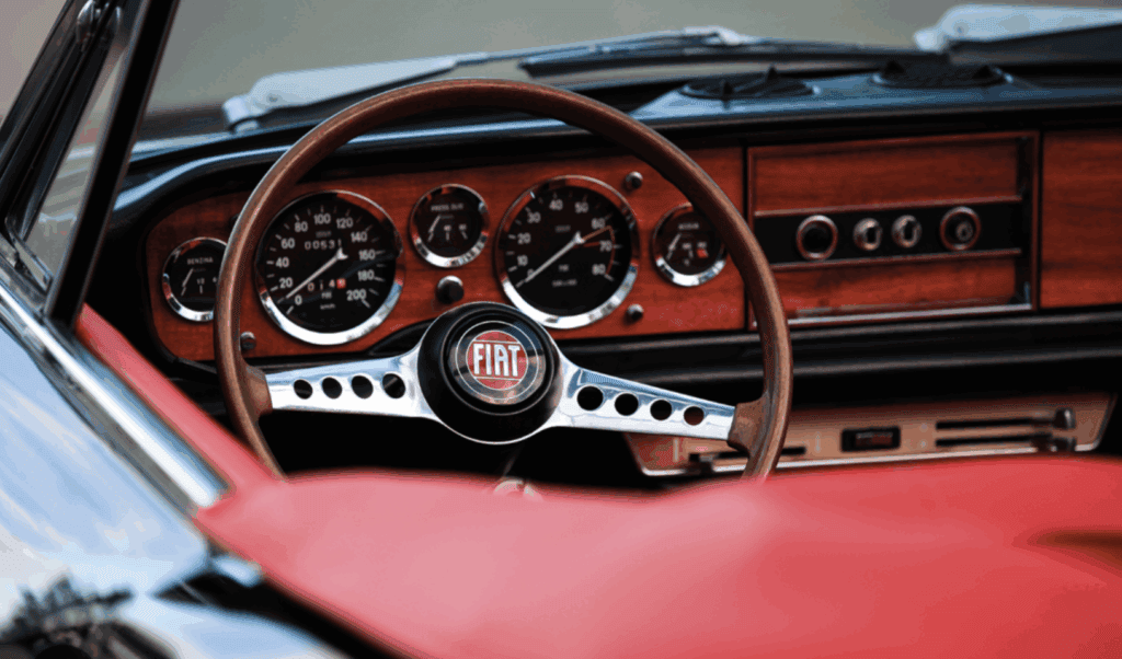 Steering wheel and dashboard of a red, 1970s Fiat Spider