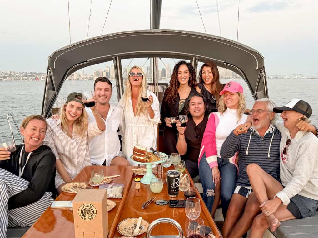 A group of people gathered around the dining table on the deck of the Riviera, holding wine glasses.