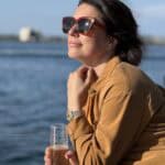 A woman with sunglasses basks in the warmth of the sun onboard the SV Riviera