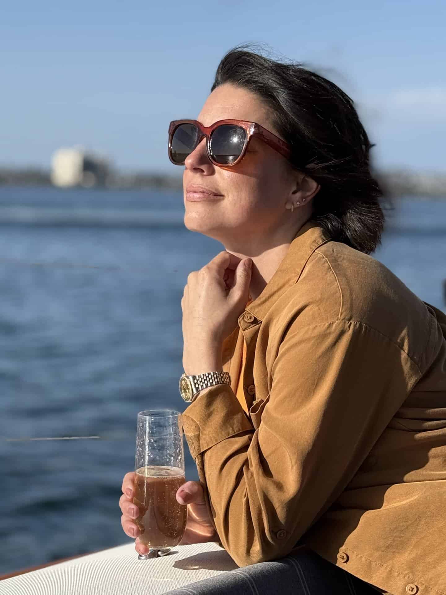 A woman with sunglasses basks in the warmth of the sun onboard the SV Riviera