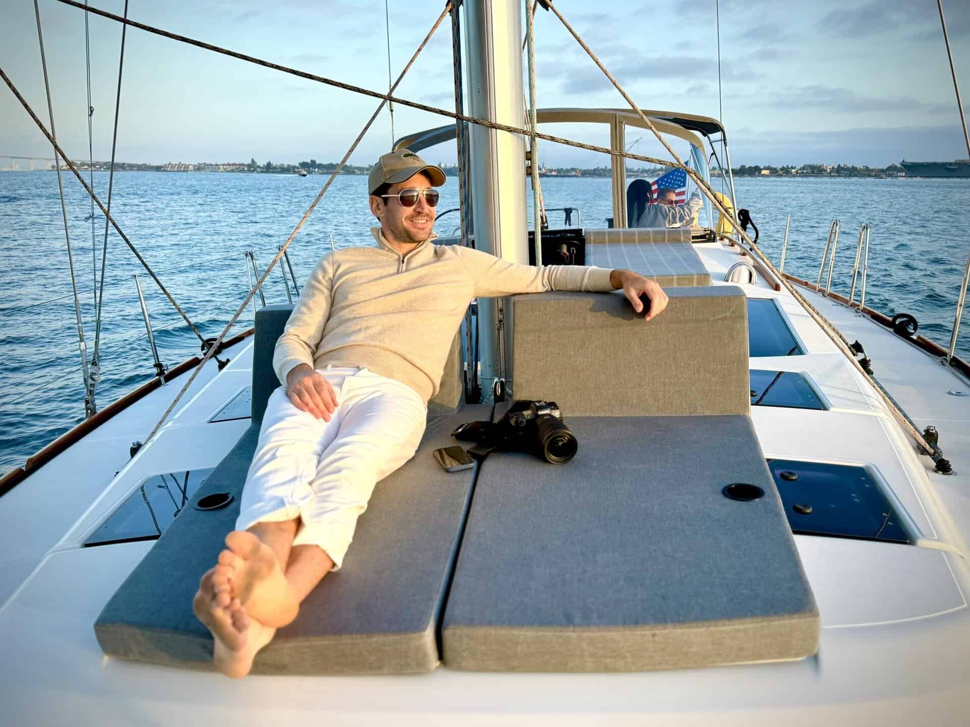 A man in a hat and sunglasses reclining with his feet up on the deck of the Riviera sailboat