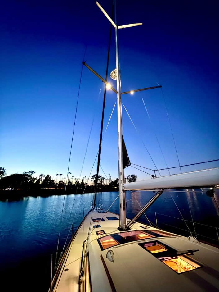 A yacht without sails docked in a harbor at dusk.