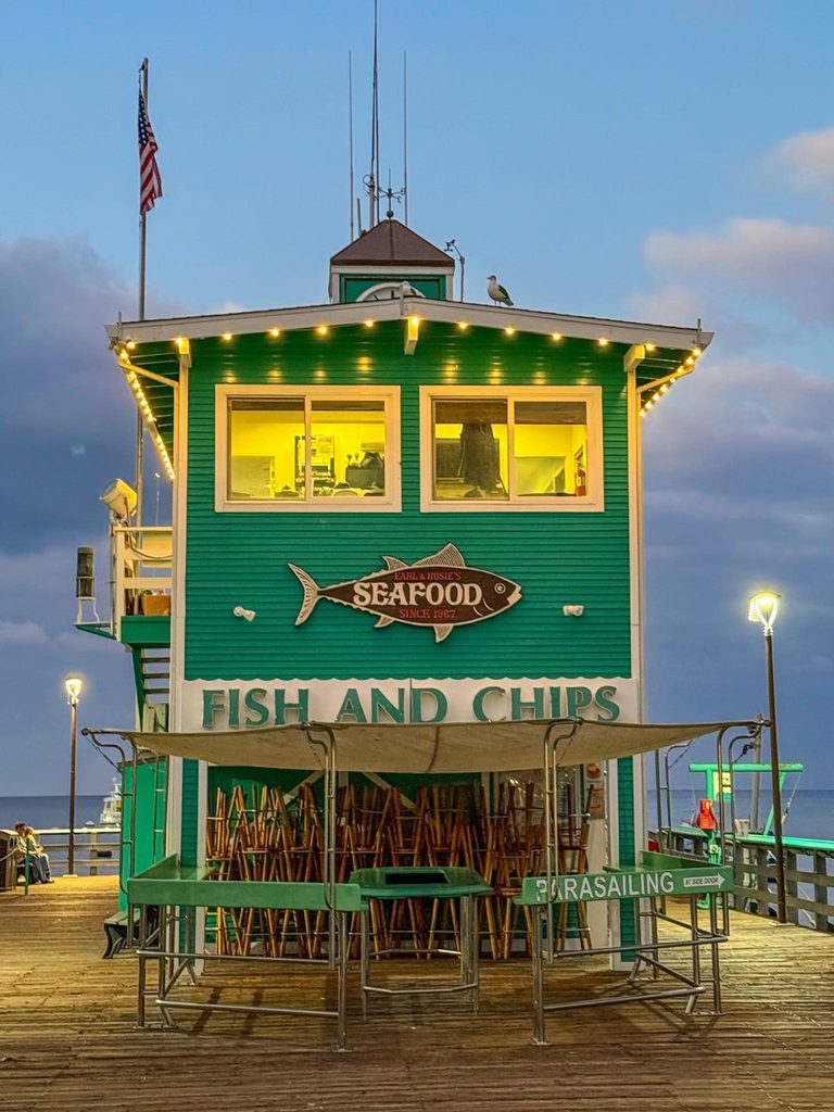 A Fish & Chips Seafood restaurant on a pier at dusk.