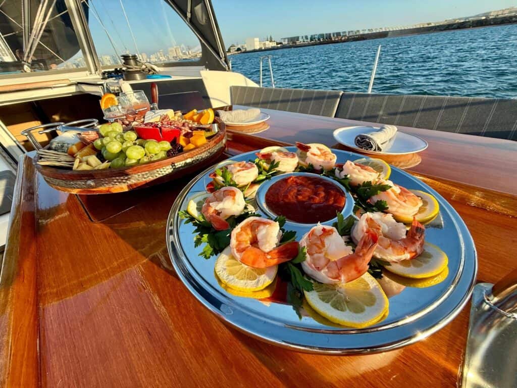Luxurious seafood platter with shrimp and lemon slices on a yacht deck, sunset over San Diego Bay.