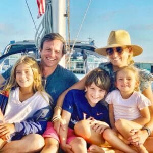 A family smiling for the camera on the deck of a sailboat.